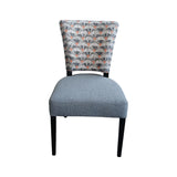 Modern upholstered dining chair with a soft grey fabric seat, an Art Deco-inspired patterned backrest in grey, charcoal and muted terracotta tones, and sleek black wooden legs. Perfect for contemporary dining rooms, restaurants, and luxury interiors.