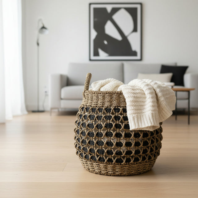 Woven basket with a white blanket on a wooden floor in a living room.