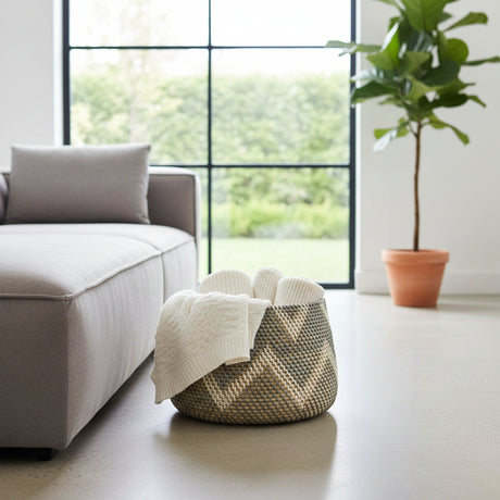 Woven basket with a blanket on a light-colored floor in a living room setting.