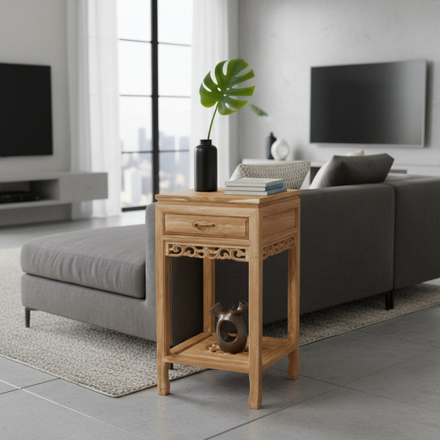 Wooden side table in a modern living room with gray sofa and large windows.