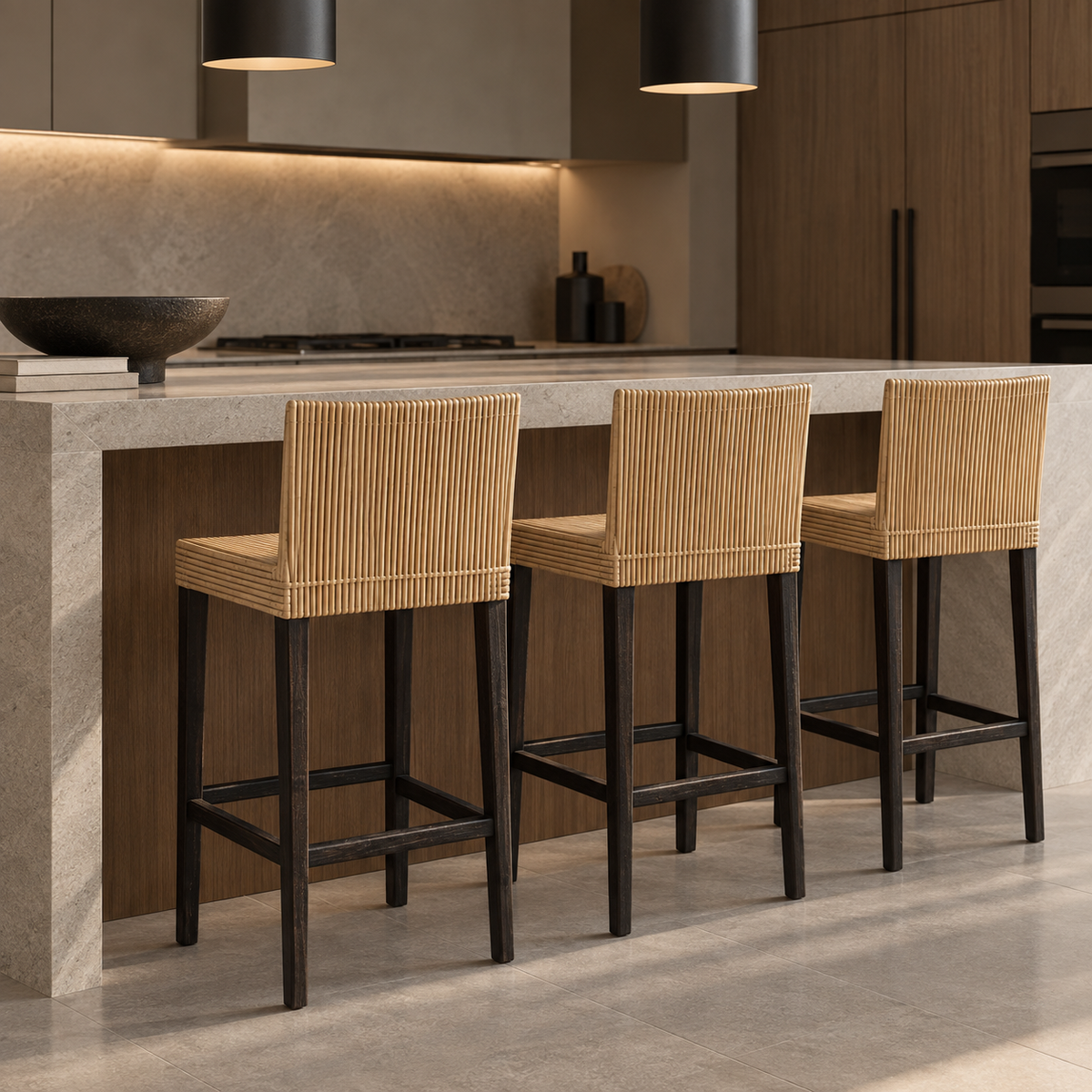 Three bar stools with natural woven seats and tall backrests, black wooden legs, and square footrests beside a kitchen island.