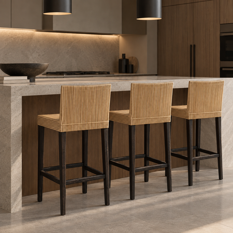 Three bar stools with natural woven seats and tall backrests, black wooden legs, and square footrests beside a kitchen island.