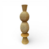 Tall handwoven sculptural floor vase featuring a natural wicker finish with a stacked organic silhouette and flared base. A striking decorative statement piece that adds warmth, texture, and artisan charm to living rooms, entryways, boutique hotels, and contemporary interiors.