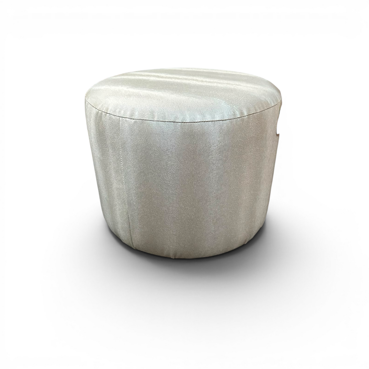 Ivory upholstered round ottoman with a minimalist design, ideal as a footrest, occasional seat, or modern accent piece for living rooms and bedrooms.