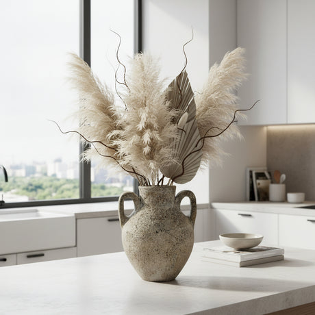 Rustic ceramic amphora vase with a textured stone finish and twin loop handles, styled with pampas grass, decorative branches, and natural botanicals on a modern coffee table, adding timeless organic elegance to contemporary interiors.