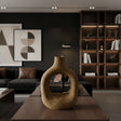 Sculptural stoneware vase with a warm earthy finish, featuring a rounded organic silhouette, large oval cut-out centre, and narrow neck. Styled on a modern coffee table, this handcrafted decorative vase adds natural texture and contemporary elegance to living spaces.