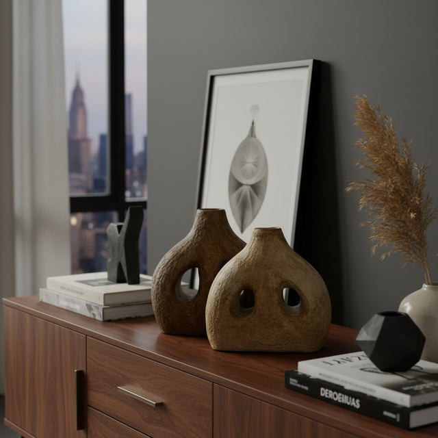 Set of two handcrafted sculptural stoneware vases in complementary earthy brown tones, featuring distinctive organic silhouettes with decorative cut-out openings. Styled on a modern console table, these contemporary statement vases add warmth, texture, and artistic character to shelves, coffee tables, and living spaces.