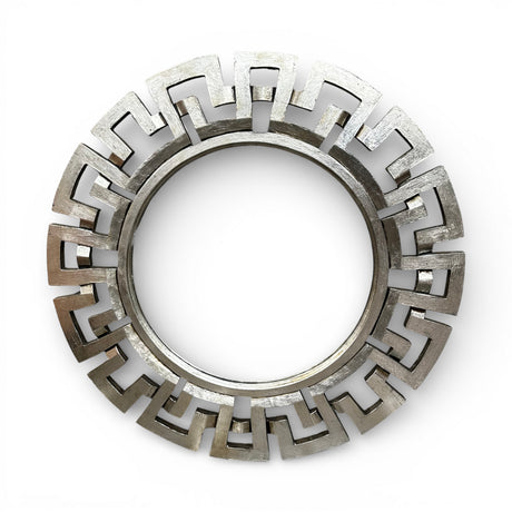 Round decorative wall mirror featuring a brushed silver geometric frame with a bold Greek key-inspired design, creating a sleek contemporary statement piece for modern interiors.