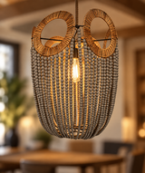 A hanging pendant light fixture with a woven circular top, a central exposed bulb, and many dangling gray beads forming a basket-like shade, shown in a softly blurred indoor room.