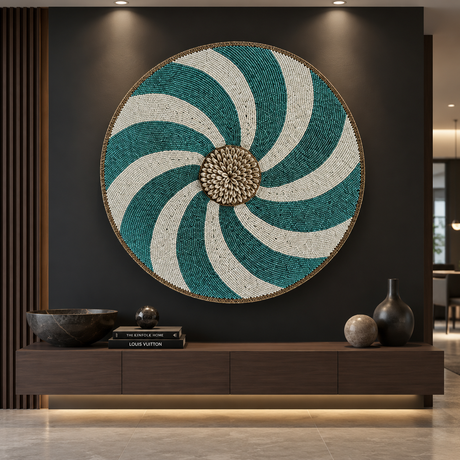Large round woven wall art with a teal and off-white spiral pattern and a metallic gold-toned center, displayed on a dark wall above a wooden console in a modern interior.