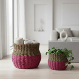 Two woven baskets with a pink bottom and green top in a room with a plant and decor items.