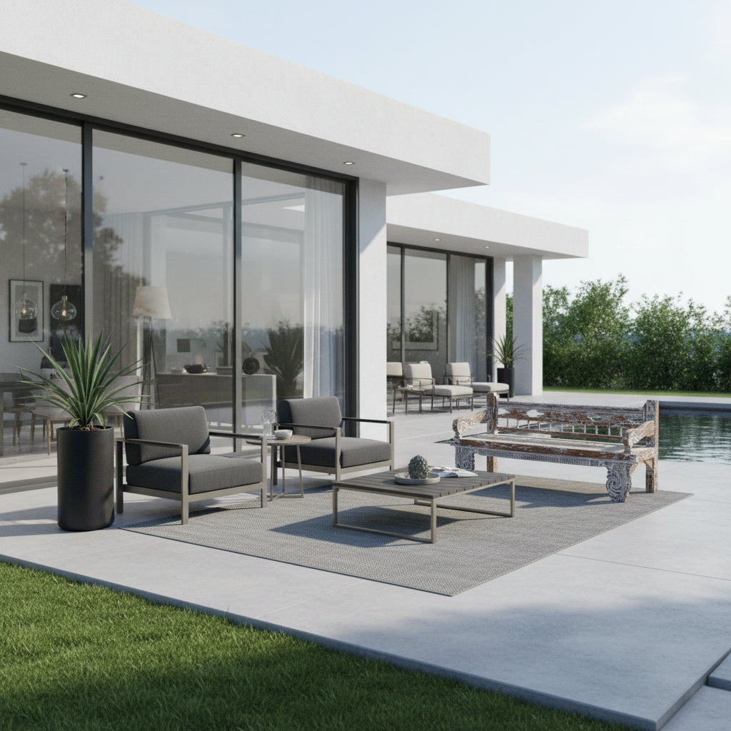 Handcrafted vintage carved wooden daybed with an intricately detailed frame and woven seat, styled on a contemporary outdoor patio beside a swimming pool with modern lounge furniture.