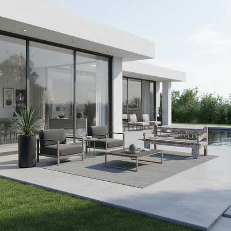 Handcrafted vintage carved wooden daybed with an intricately detailed frame and woven seat, styled on a contemporary outdoor patio beside a swimming pool with modern lounge furniture.