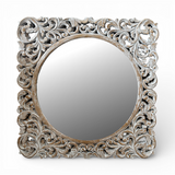 Whitewashed ornate carved wooden wall mirror featuring an intricately hand-carved botanical frame with a distressed natural finish and round mirror centre. This elegant statement mirror adds timeless sophistication to entryways, living rooms, bedrooms, and hallways while complementing coastal, farmhouse, French country, traditional, and luxury interiors.