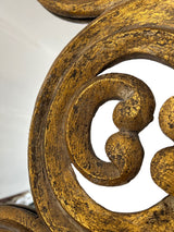 Close-up of an ornate wall mirror featuring sculpted scrollwork with a distressed antique gold finish, highlighting its handcrafted texture and luxurious decorative detail.