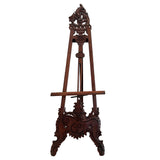 Elegant hand-carved dark wood display easel featuring intricate floral scrollwork and an antique finish, ideal for showcasing artwork, mirrors, signs, or decorative plates.