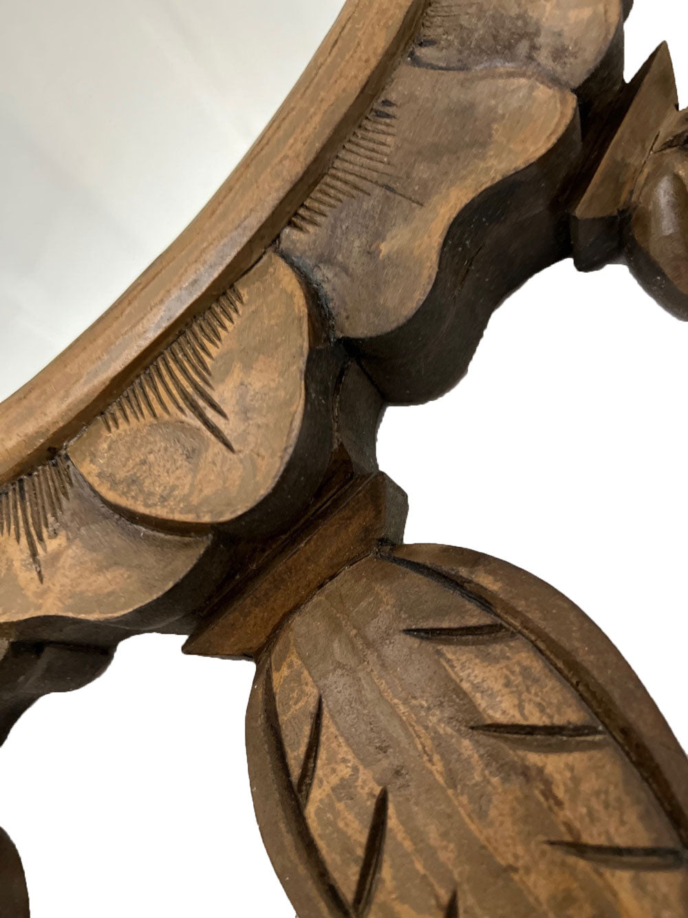 Close-up of a handcrafted wooden wall mirror featuring intricately carved leaf detailing, natural wood grain, and a warm distressed finish for timeless interior décor.