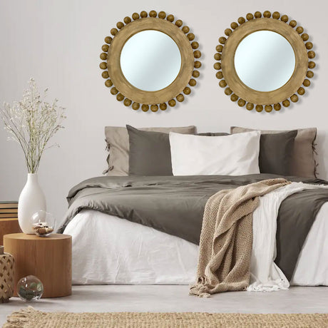 Set of two round gold beaded wall mirrors with distressed wooden frames, beautifully styled above a modern bed to create a warm, elegant focal point in a contemporary bedroom.