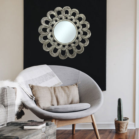Elegant round wall mirror featuring a sculptural silver petal frame with layered loop detailing, styled as a statement piece in a contemporary living space.