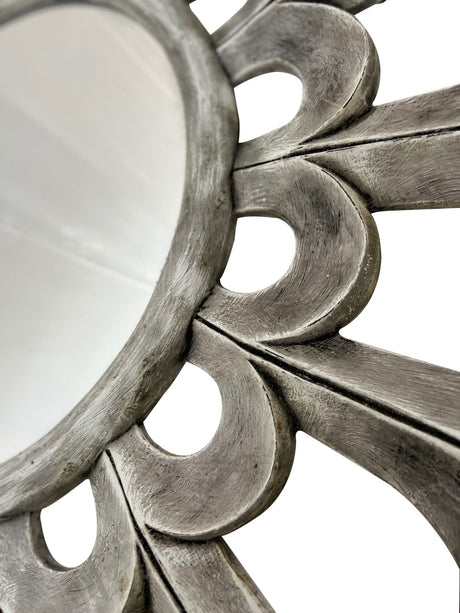 Close-up of a round wall mirror featuring sculptural petal detailing with a distressed silver finish, highlighting its handcrafted texture and elegant decorative design.