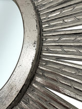 Close-up of an elegant silver sunburst wall mirror featuring a textured radial frame with a distressed metallic finish, highlighting its handcrafted detail and sophisticated design.