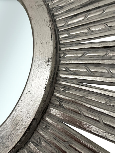 Close-up of an elegant silver sunburst wall mirror featuring a textured radial frame with a distressed metallic finish, highlighting its handcrafted detail and sophisticated design.